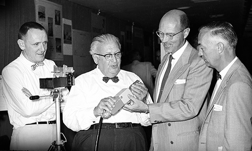 Gathering around optical equipment in 1958