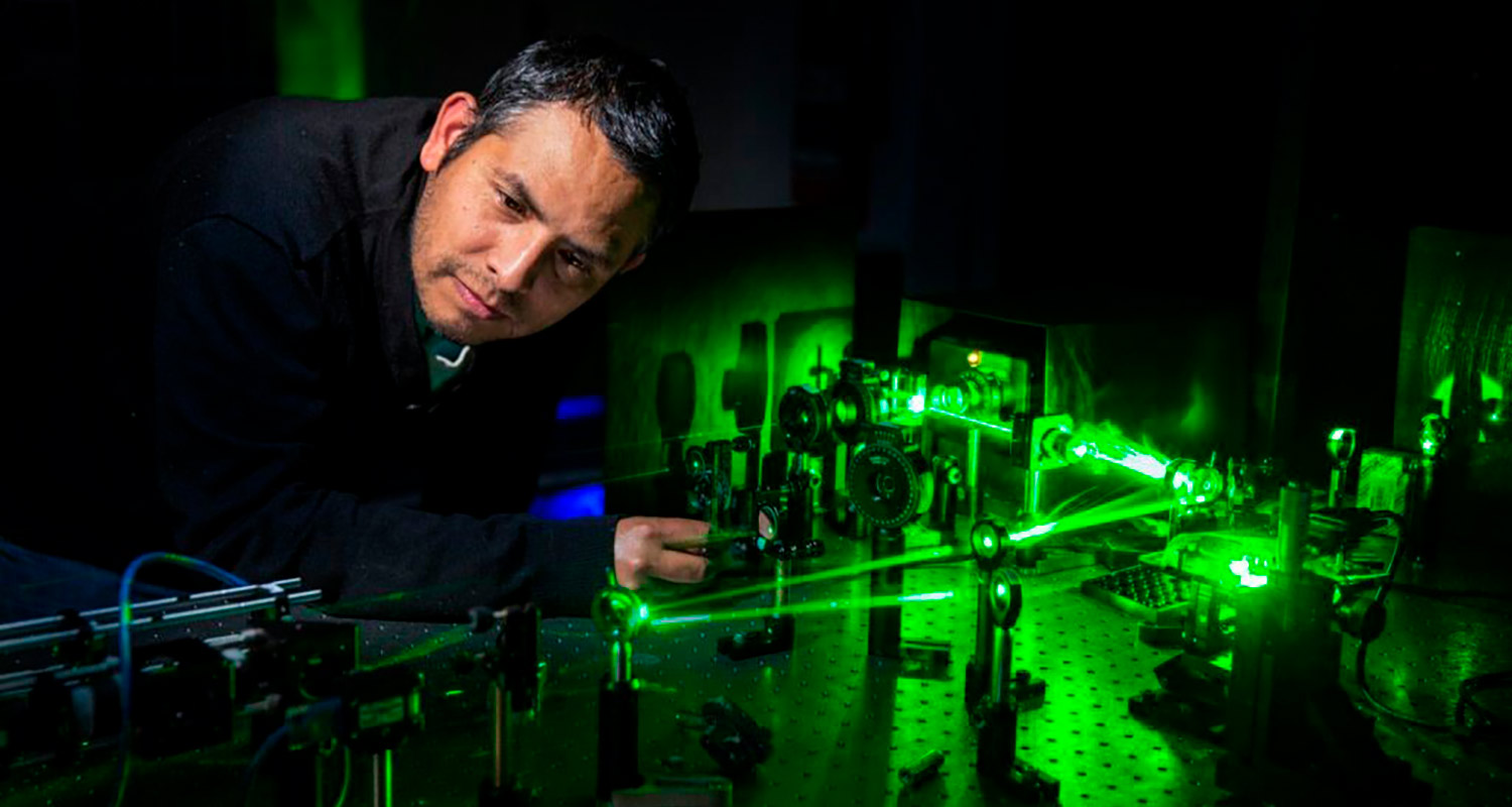 Carmelo Rosales-Guzmán leaning over a laser table