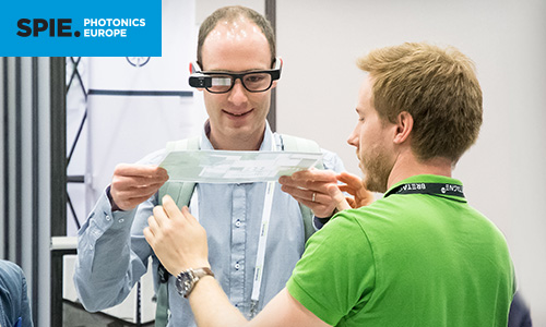 Two men marvel at the power of augmented reality glasses at SPIE Photonics Europe exhibition
