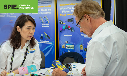 Man and woman discuss laser technology at the SPIE Optics and Photonics exhibition