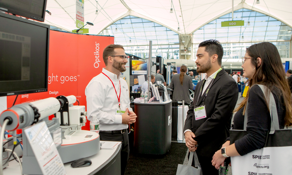 Attendees greet an exhibitor in his attractive booth space
