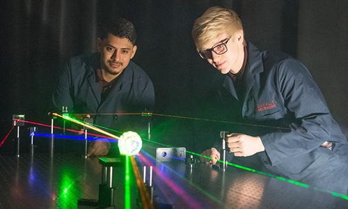 Two young men gather around a laser