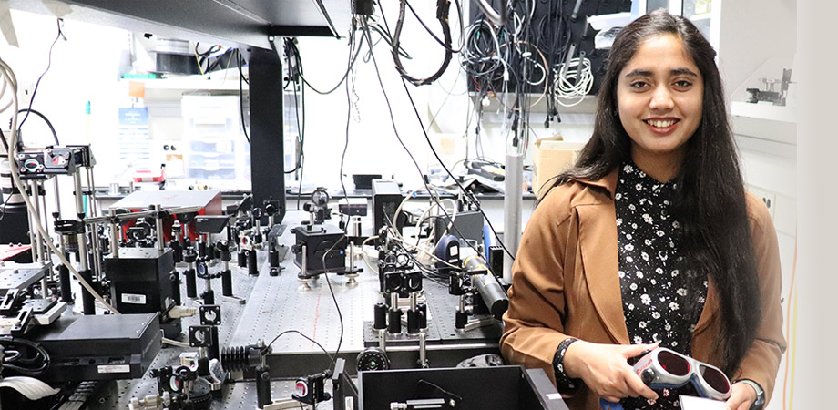 Quazi Rushnan Islam Next to a custom-built Titanium: Sapphire laser designed to produce short red pulses. Islam is holding an IR card which she uses to follow the beam path of the output.