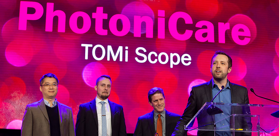 Shelton giving his 2020 Prism Award acceptance speech for PhotoniCare’s winning technology, the TOMi Scope, which was recently re-branded as the OtoSight Middle Ear Scope. On stage with Shelton are PhotoniCare team members. Left to right: former Director of R&D Wei Kang, co-founder and VP of Clinical Operations Ryan Nolan, and Stephen Boppart.
