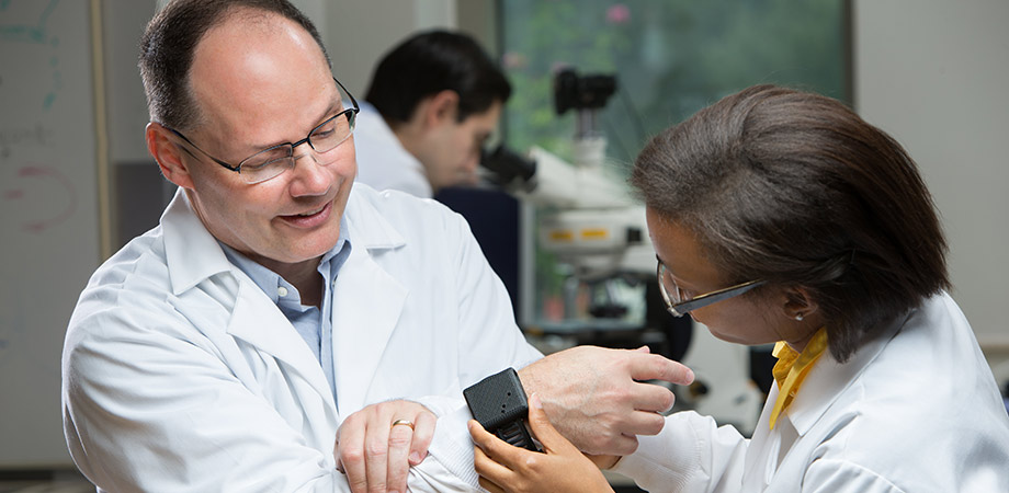  Dr. Andrea Locke demonstrating one of the wearable optical biosensor prototypes on Dr. Gerard Coté