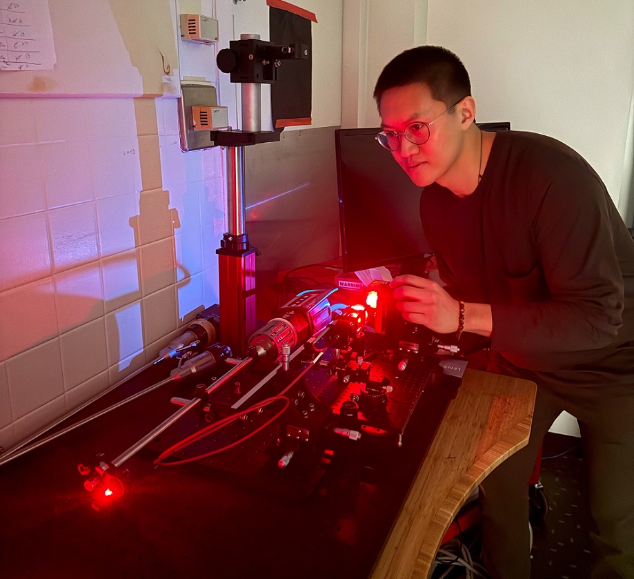 Graduate researcher Anthony Song is shown operating the optical setup