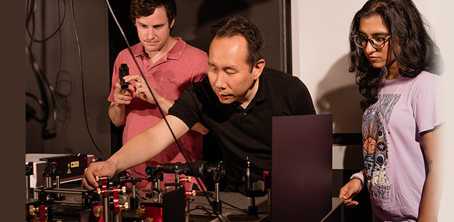 Boston University College of Engineering Associate Professor Jerry Chen, center, with senior scientist Andrew Blaeser to the left, and former undergraduate research assistant Rhea Singh to the right, working with a Quadroscope, a custom, two-photon mesoscope. Credit: Christopher McIntosh.