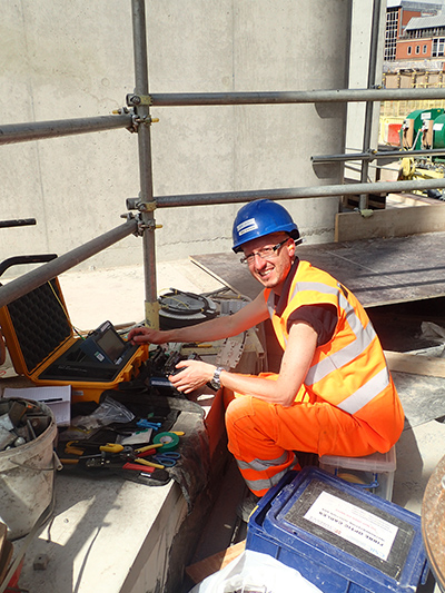 Nicky de Battista of University of of Cambridge testing the fiber-optic cable connections at the Principal Tower construction site